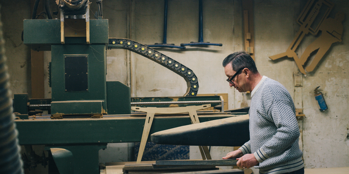 Photo of Simon Cass in the workshop, handling timber for a new project.