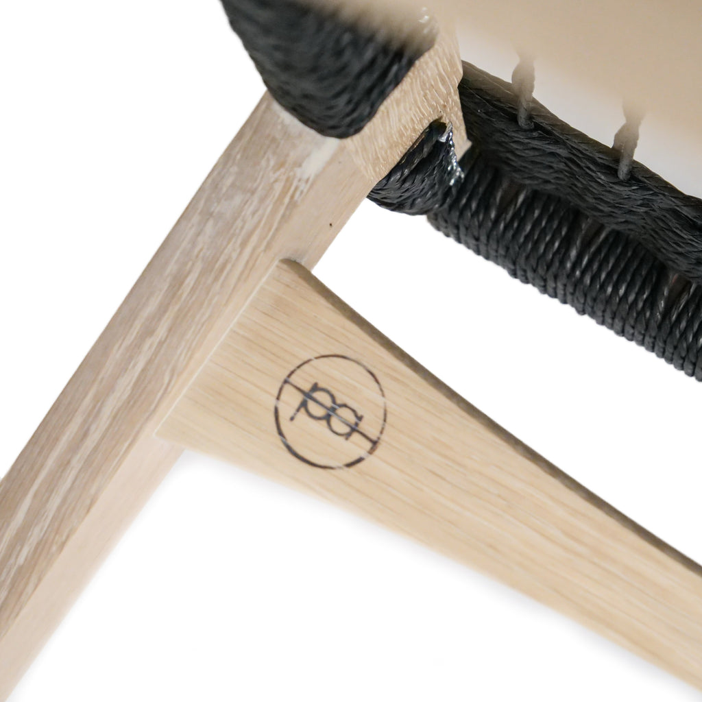 Photo close up of a limed oak pi stool frame, the par-avion co. logo visible.