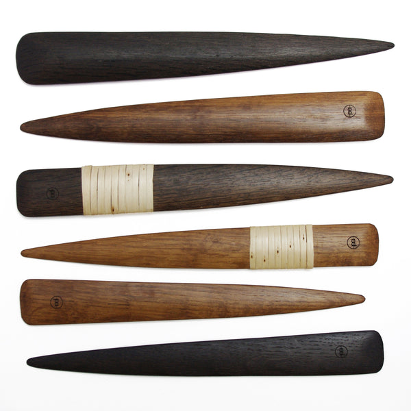 Photo of various bog oak letter openers lined up on a white background, top to bottom: plain black, plain brown, wrapped black, wrapped brown, plain brown, plain black.