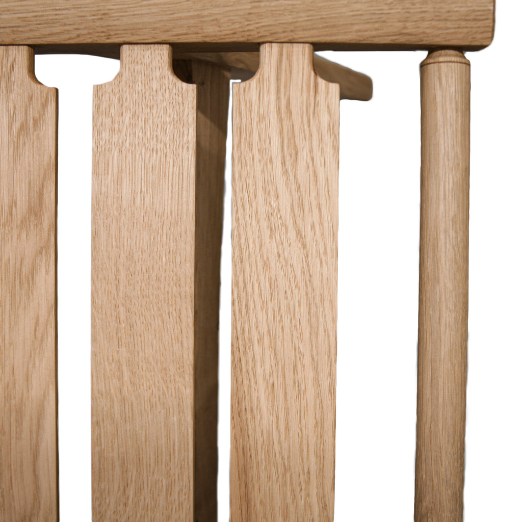 Photo close up of a slatted seat on a natural oak pi2 stool frame on a white background.