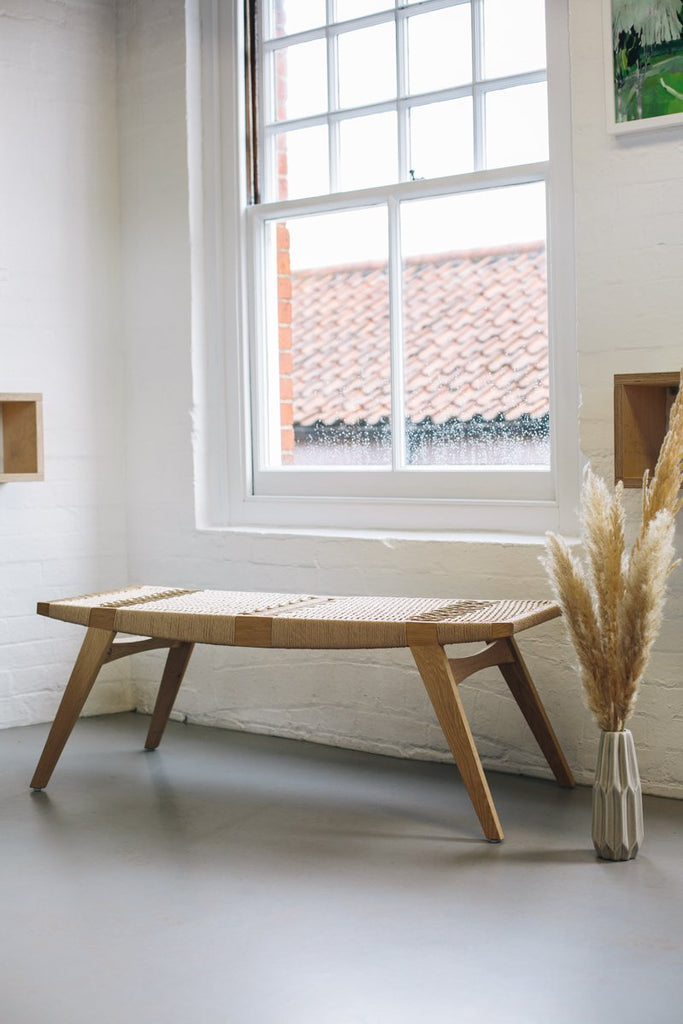 Photo of a natural oak and natural Danish Cord pi3 stool under a window in front of a white brick wall.
